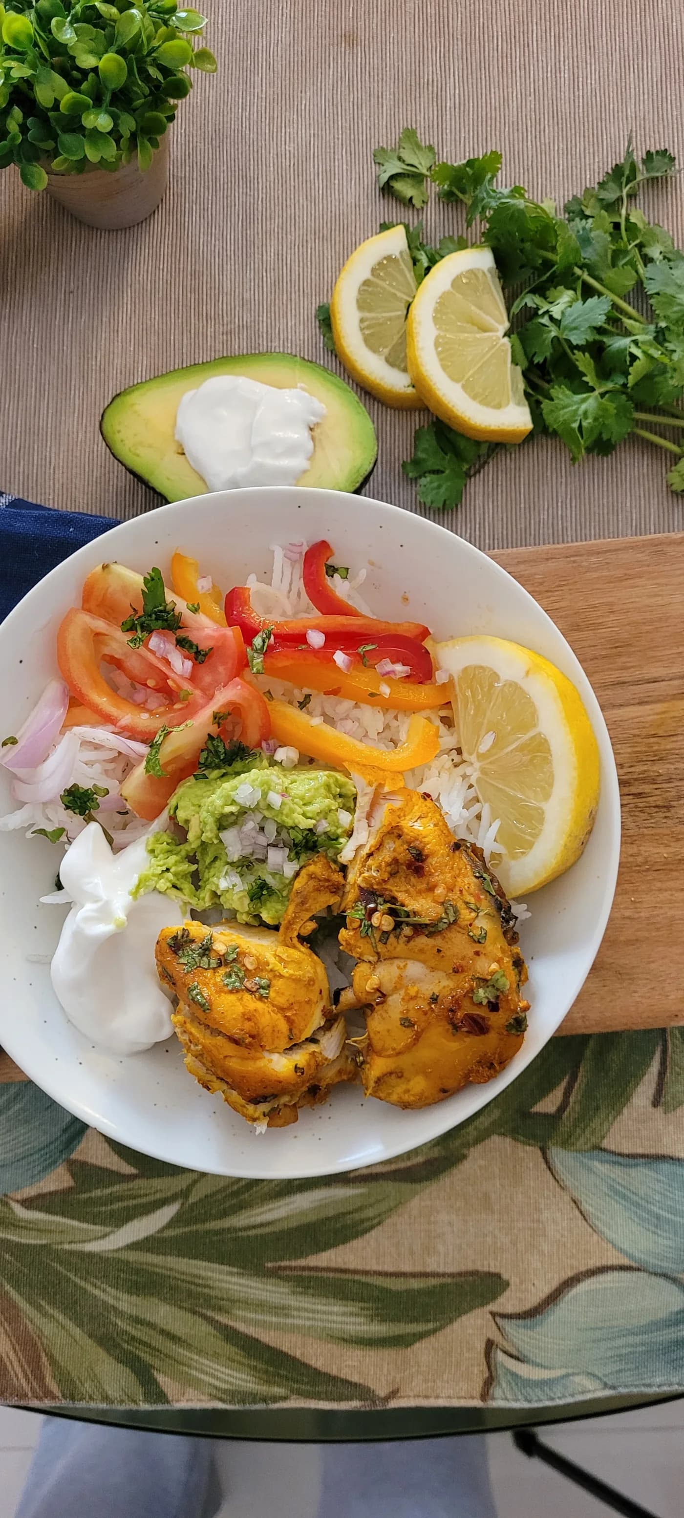 Healthy chicken burrito bowl with seasoned chicken, rice, vegetables, avocado, lemon, and yogurt sauce
