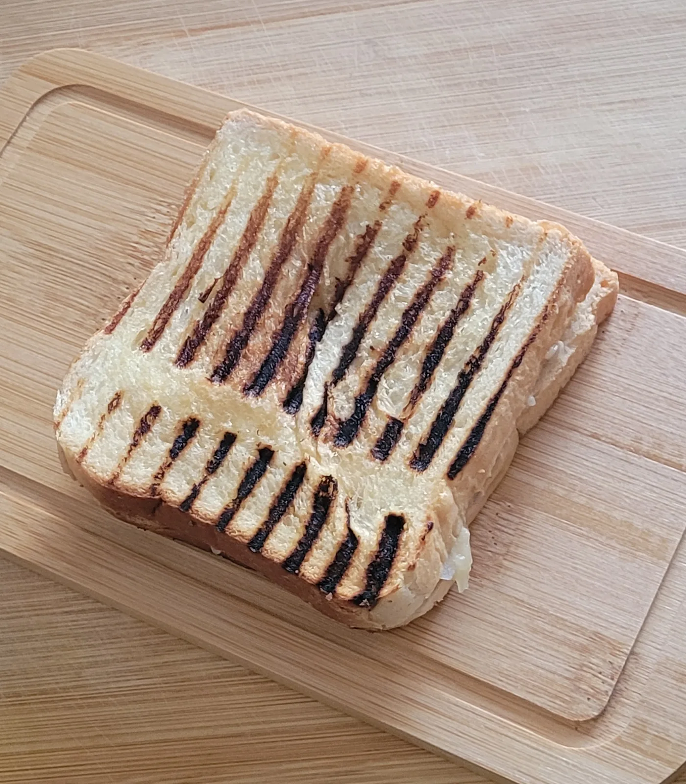 Grilled tuna and cheese sandwich with crisp grill marks on a wooden board