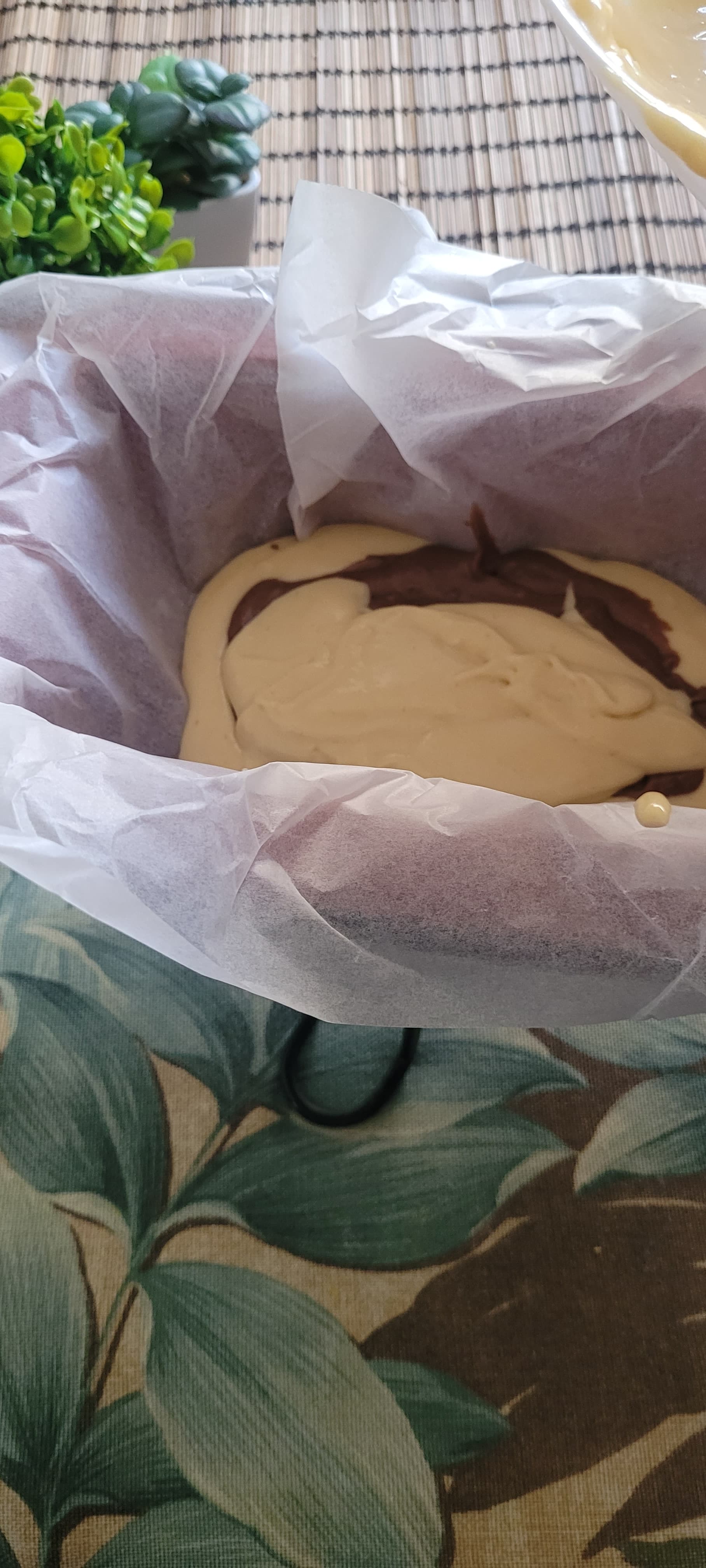 Chocolate and vanilla cake batters layered in a lined baking pan