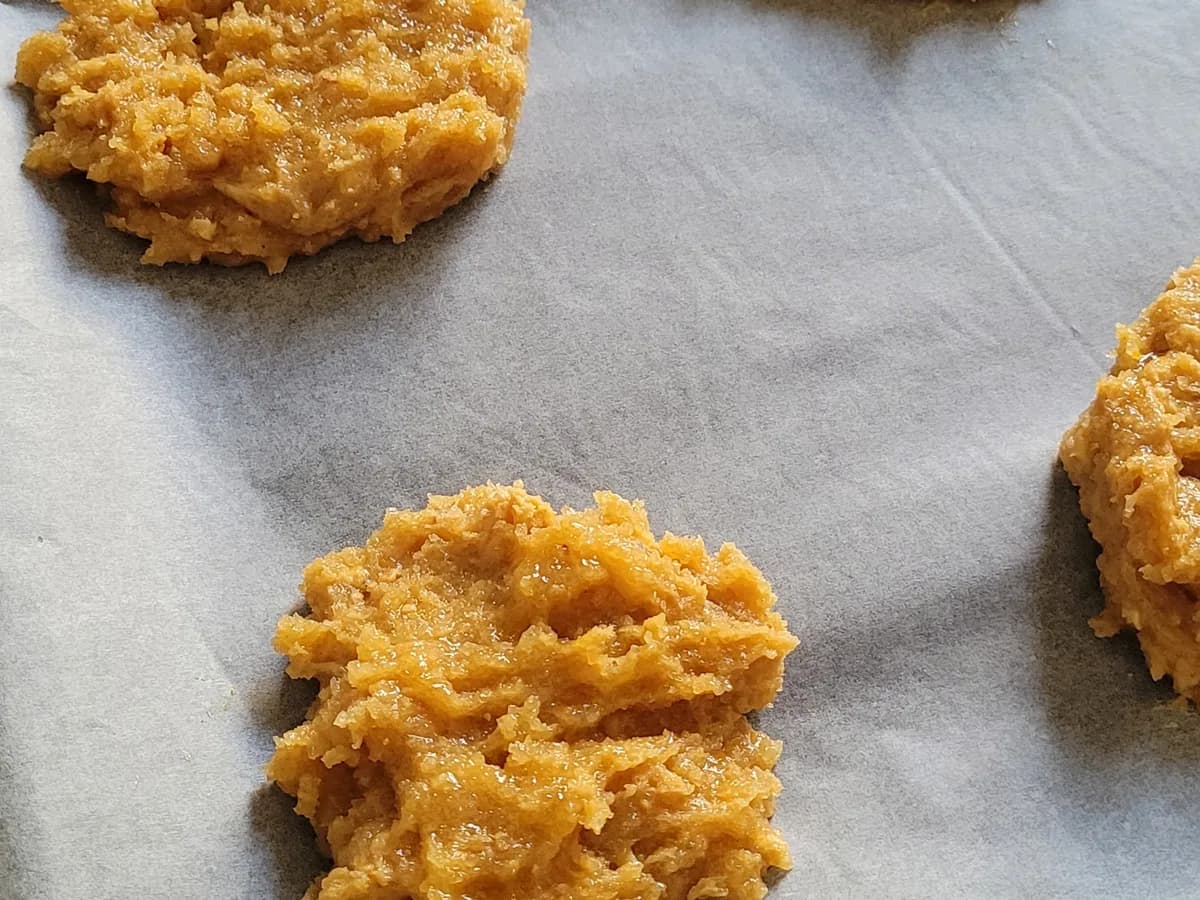 Peanut butter cookie dough portions arranged on parchment before baking