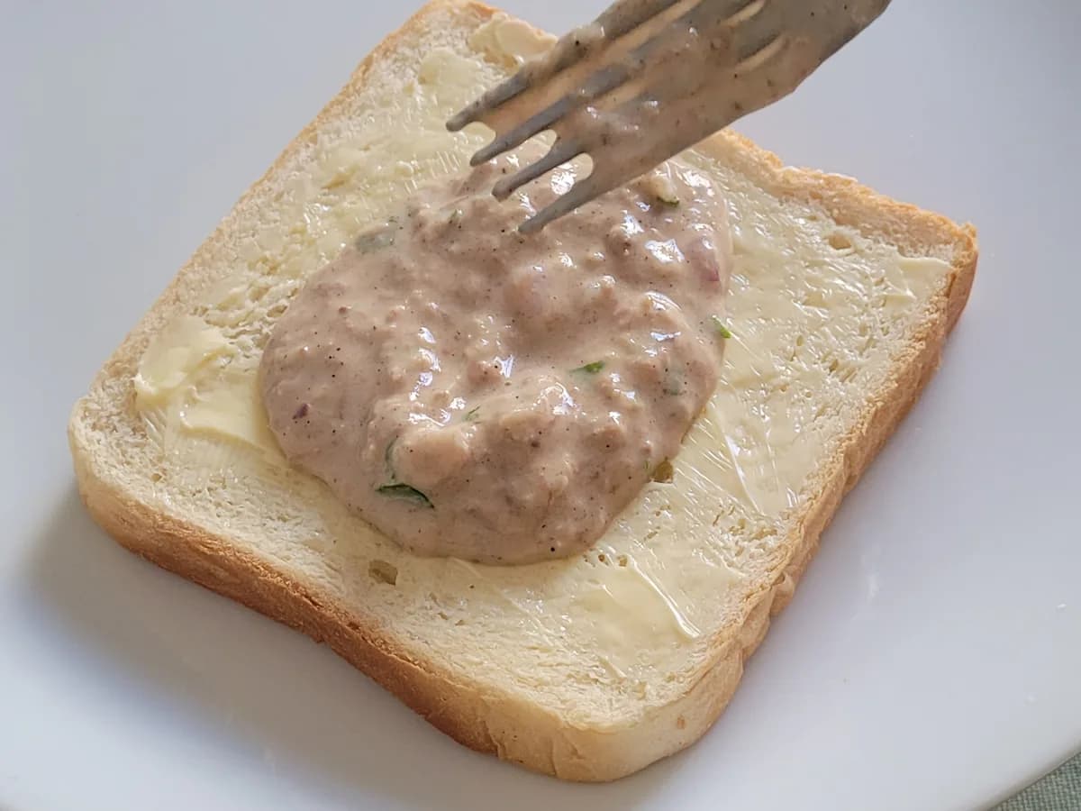 Tuna filling spread over a slice of sandwich bread